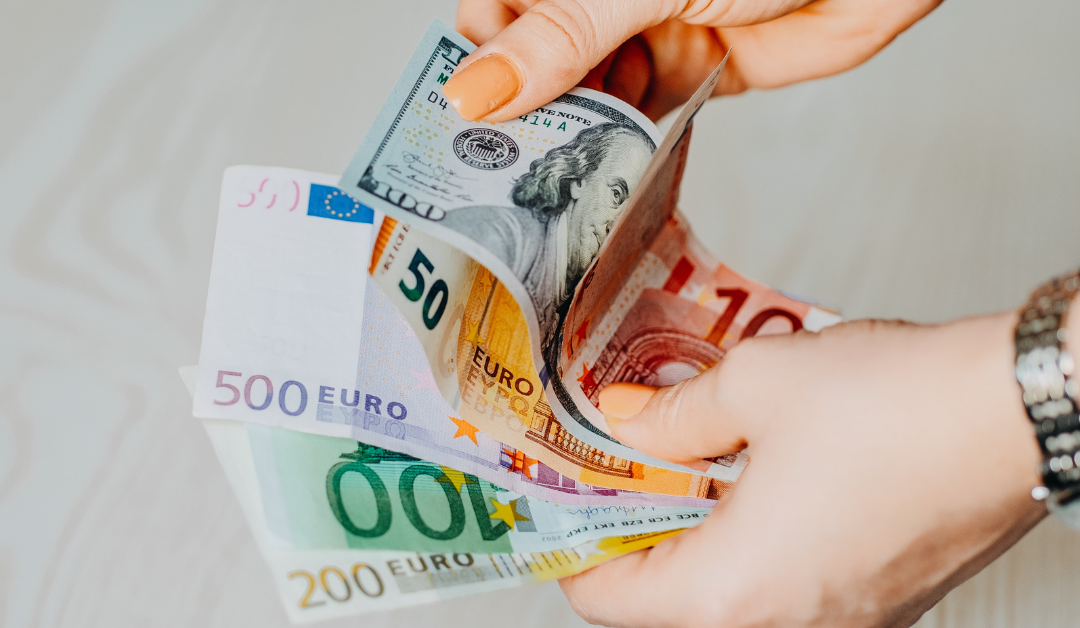 Hands holding revenue in Dollars and Euros