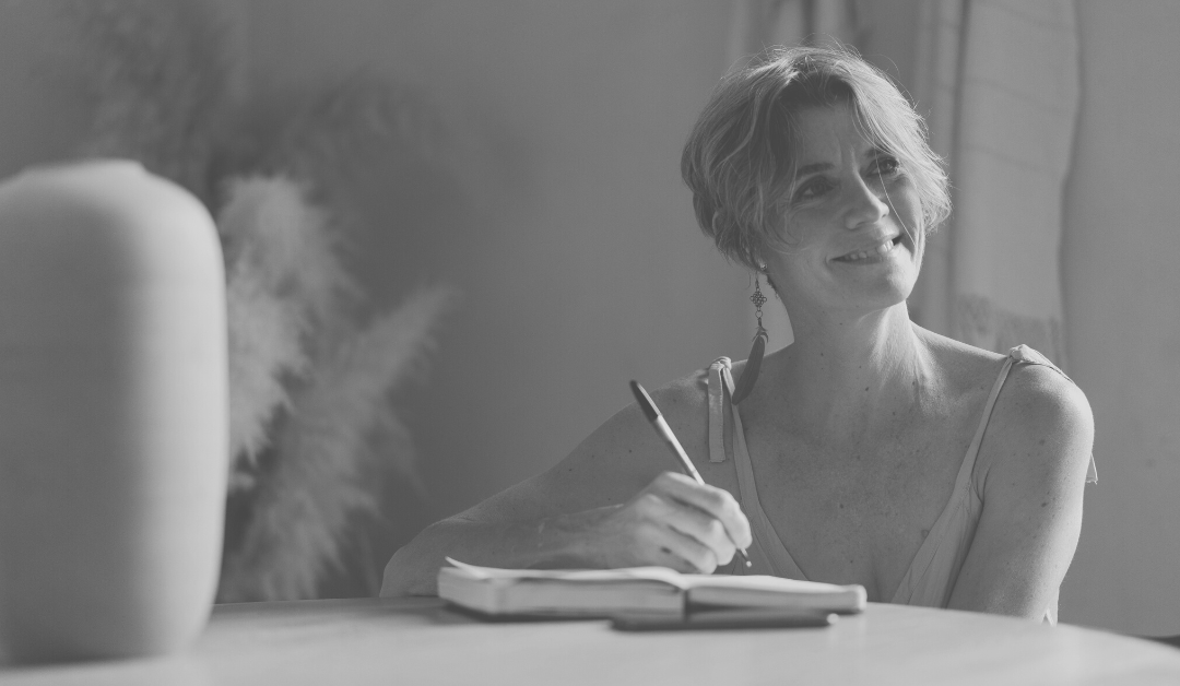 Person sitting at a table writing intentions in a notebook